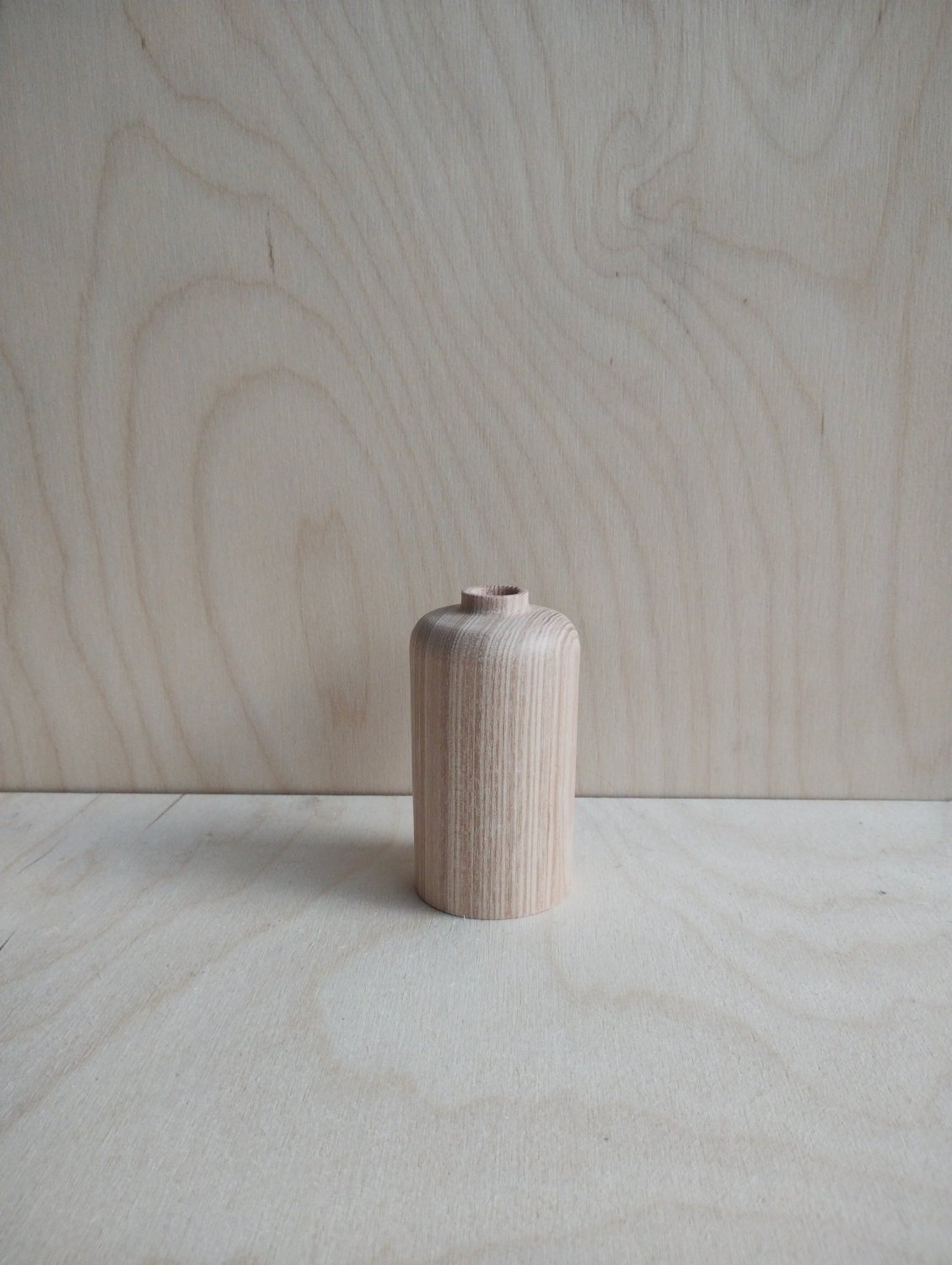 Small light-wood vase with vertical grain pattern and flat round base