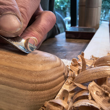 atelierbeeld van handgemaakte houten objecten in Oostduinkerke beitel die houtkrullen aan het snijden is