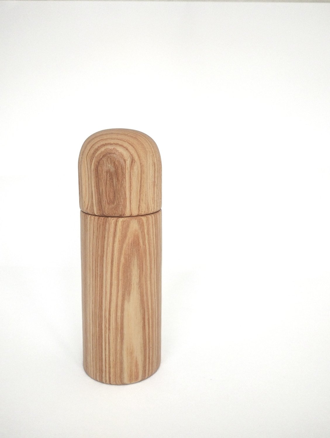 Light wood pepper grinder with rounded top and smooth cylindrical body