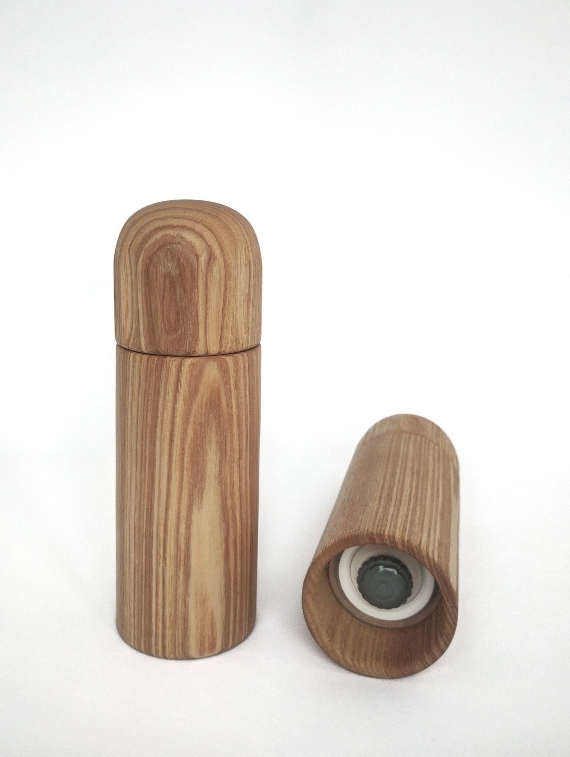 Light wood pepper grinder with cap off, showing grinding insert inside