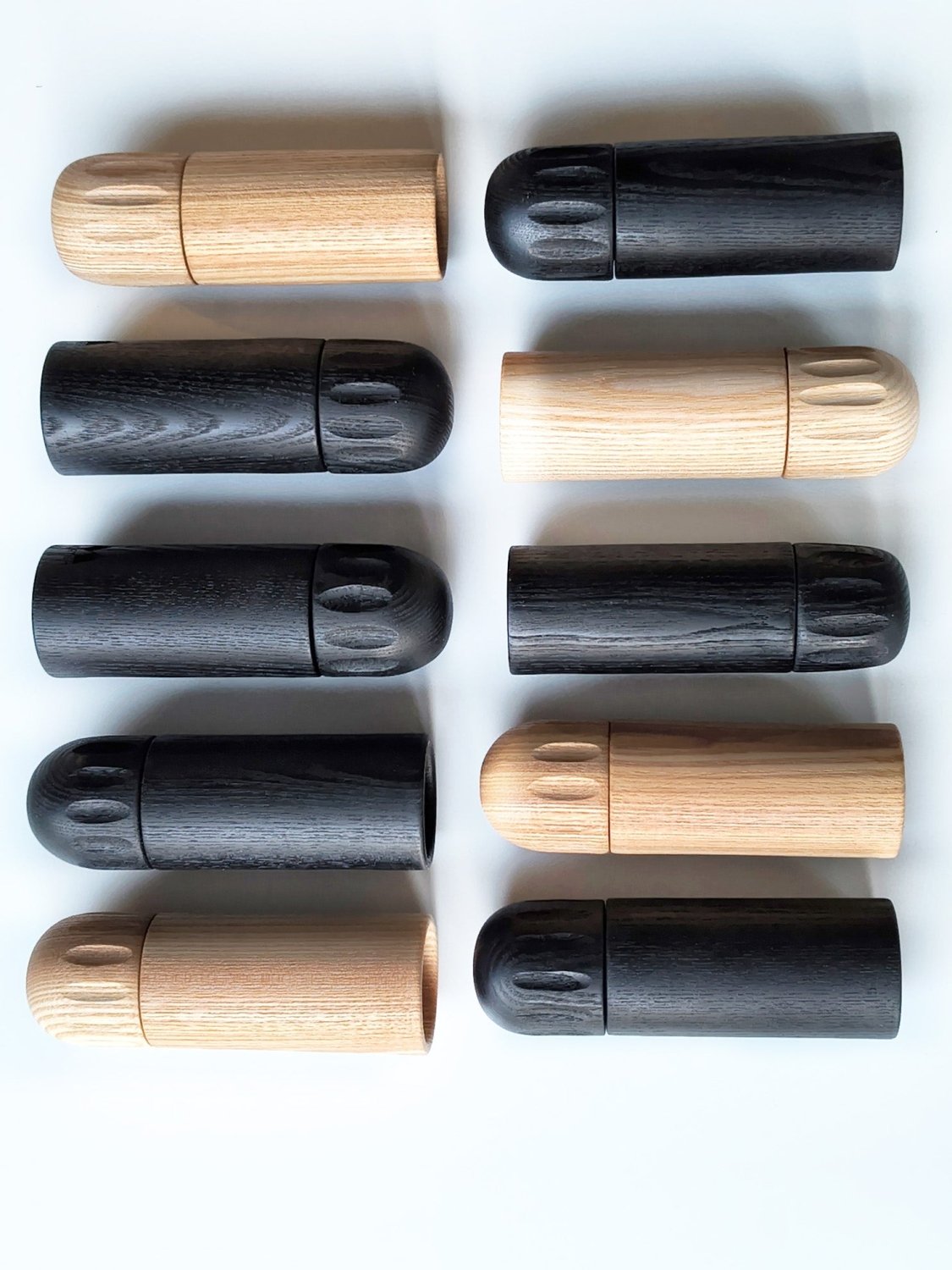 Assorted wooden pepper grinders in black and light wood, shown with caps and bodies1621243260e1af0c20-1