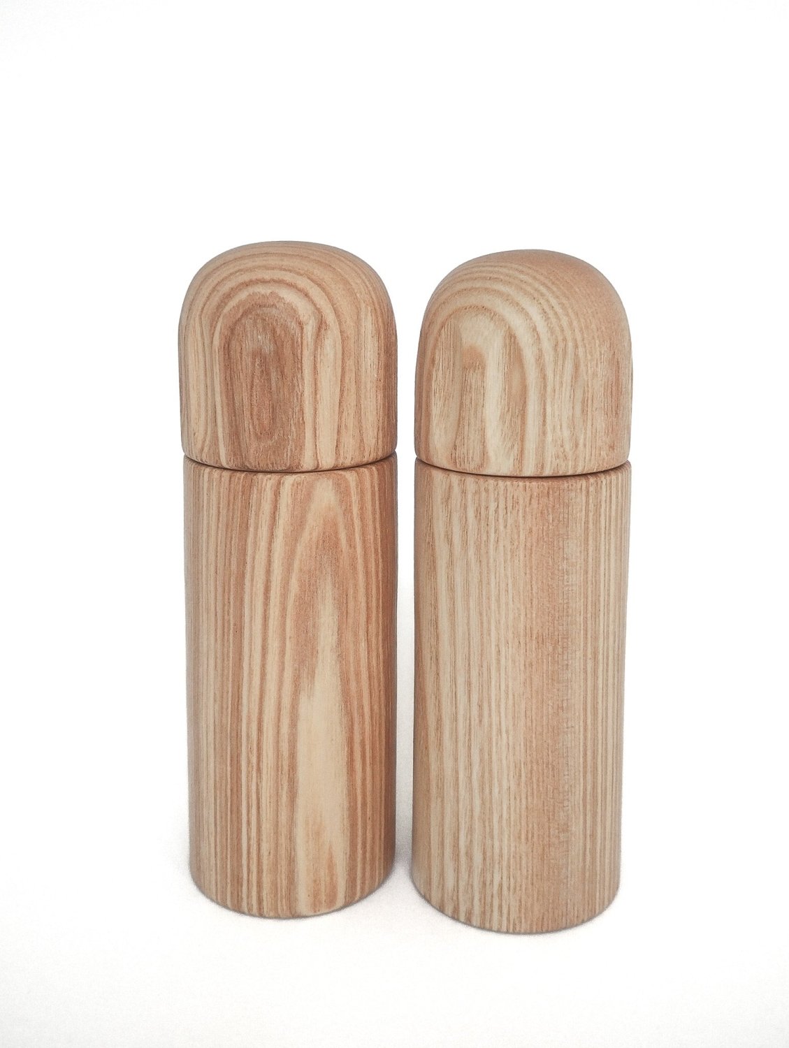Two light wood pepper grinders with rounded tops and smooth cylindrical bodies