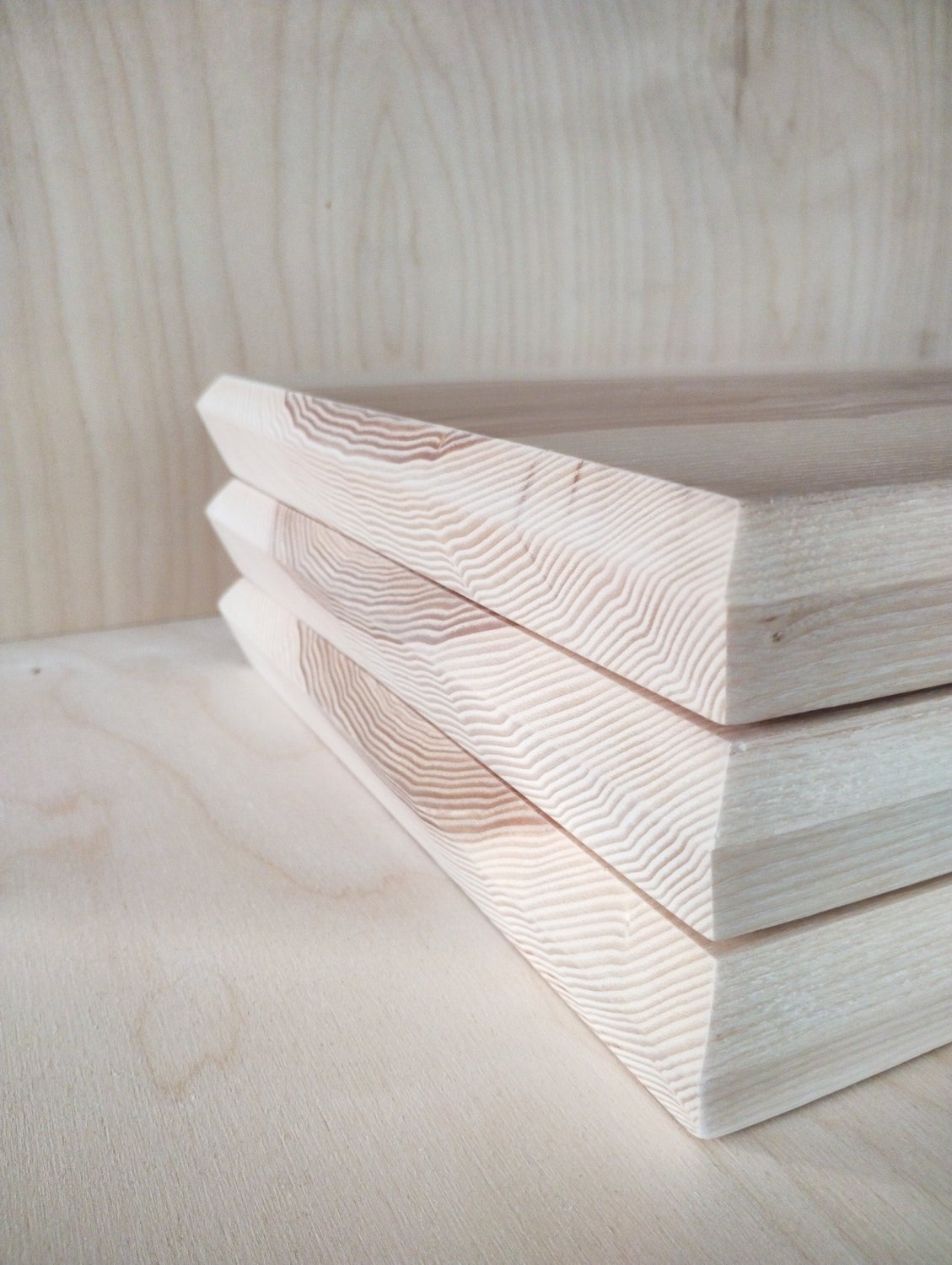 Side angle of stacked ash chopping boards with smooth faces and wood stripes.