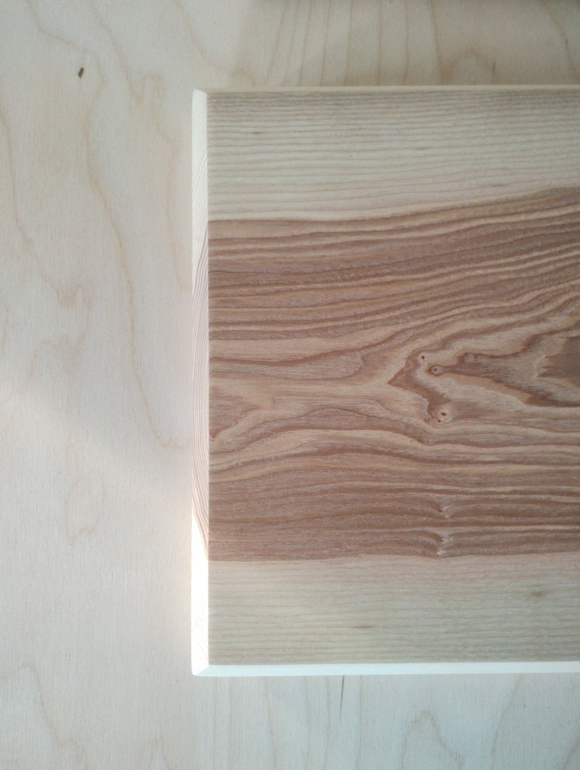 Ash chopping board corner detail with darker layered wood grain and smooth finish.
