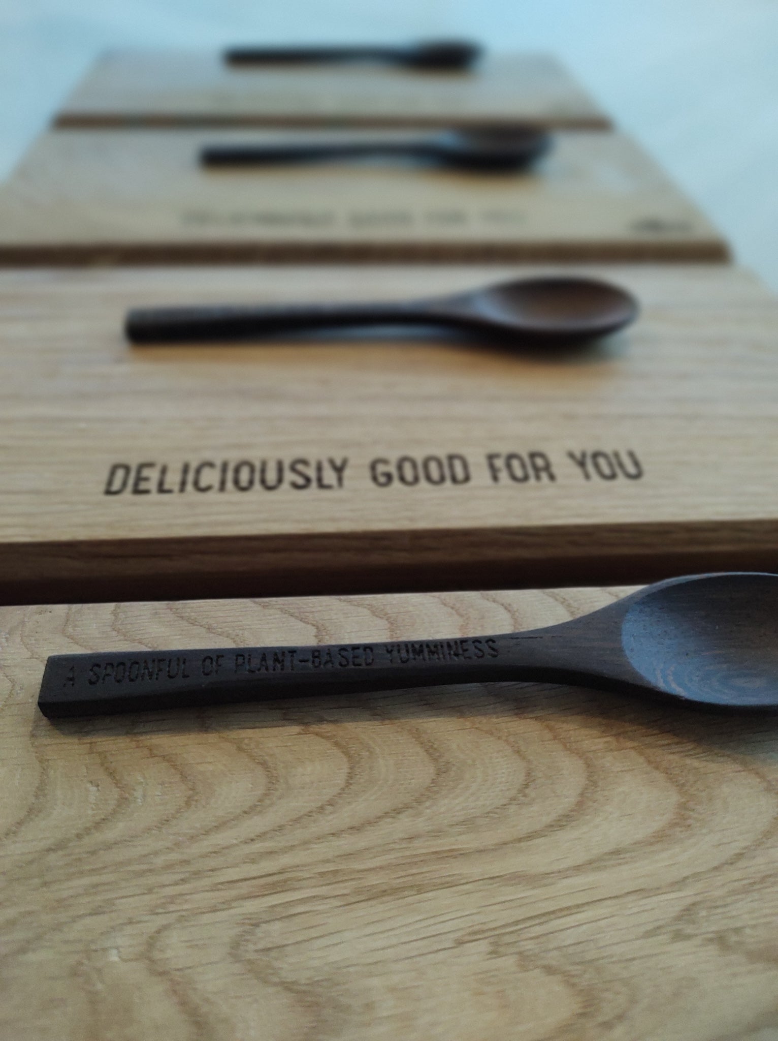 A beige wooden cutting board with a logo engraved on the side, placed on a wooden surface.1621243260e1af0c20-2