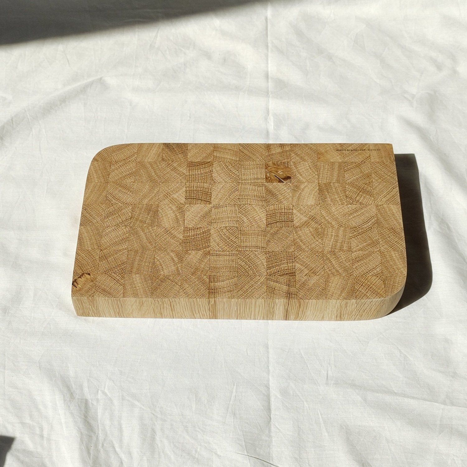 Wooden cutting board side view with patchwork surface and rounded corners