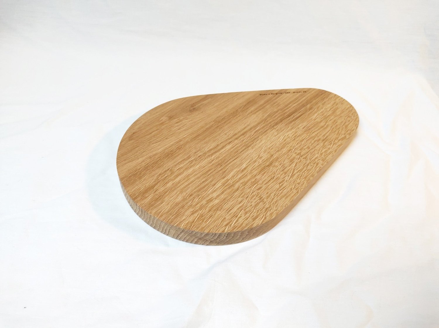 Large wooden pear-shaped cutting board with angled edge and visible grain