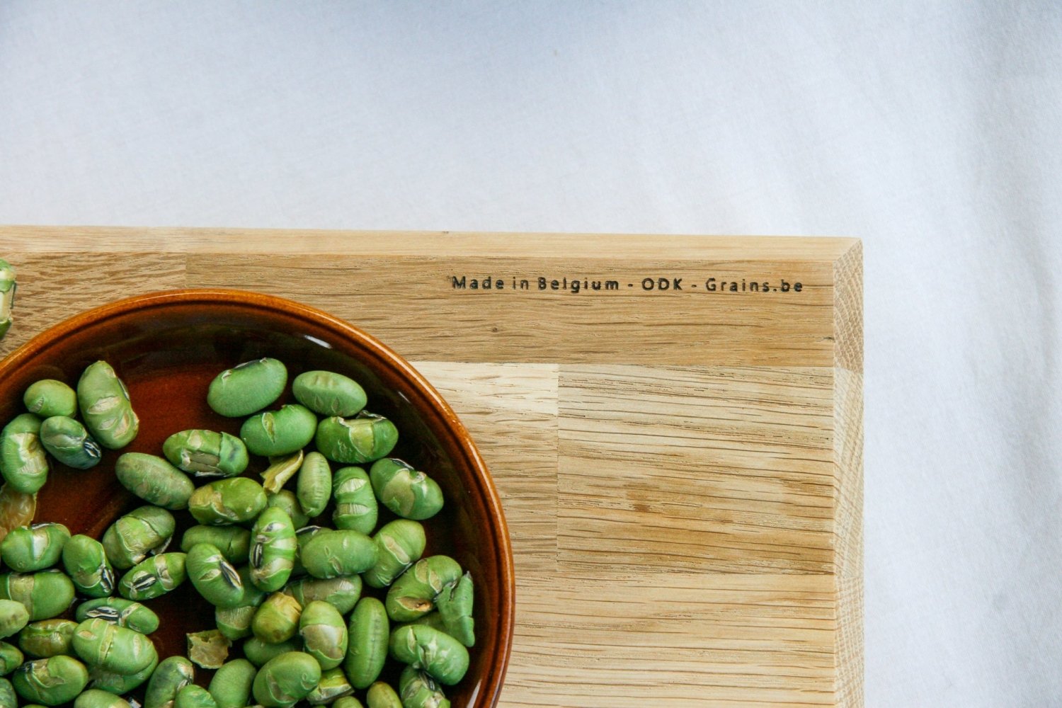 Wooden chopping board with green vegetables and a stamped marking near the edge