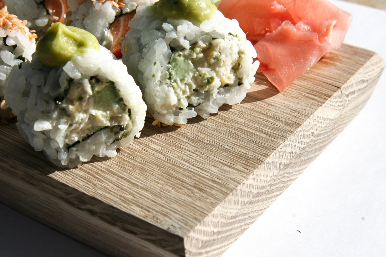 Wooden serving board with assorted sushi rolls and a salmon-colored piece