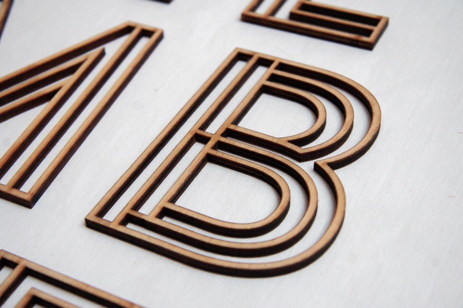 Wooden letter B with layered dark and light brown wood stripe edges