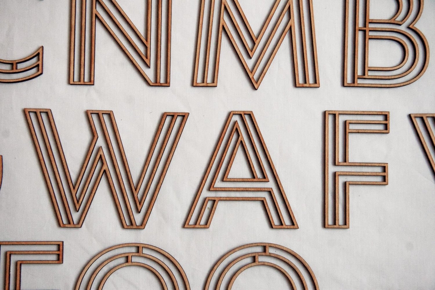 Wooden alphabet letters with thin tan and dark brown layered outlines